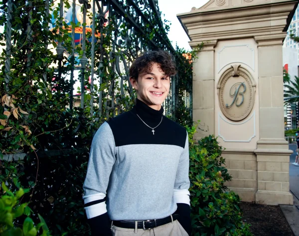 Las Vegas Strip senior portraits senior guy in a gray and black sweater posing near an elegant gate entrance