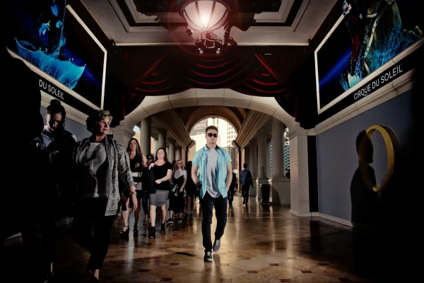 Las Vegas Strip senior portraits senior boy walking indoors near Bellagio with people in the background