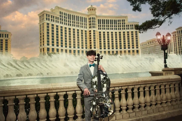 Las Vegas Strip senior portraits senior boy in a suit playing cello in front of the Bellagio fountains
