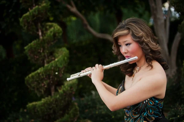 Las Vegas Strip senior portraits senior girl playing flute outdoors near greenery at Caesars Palace